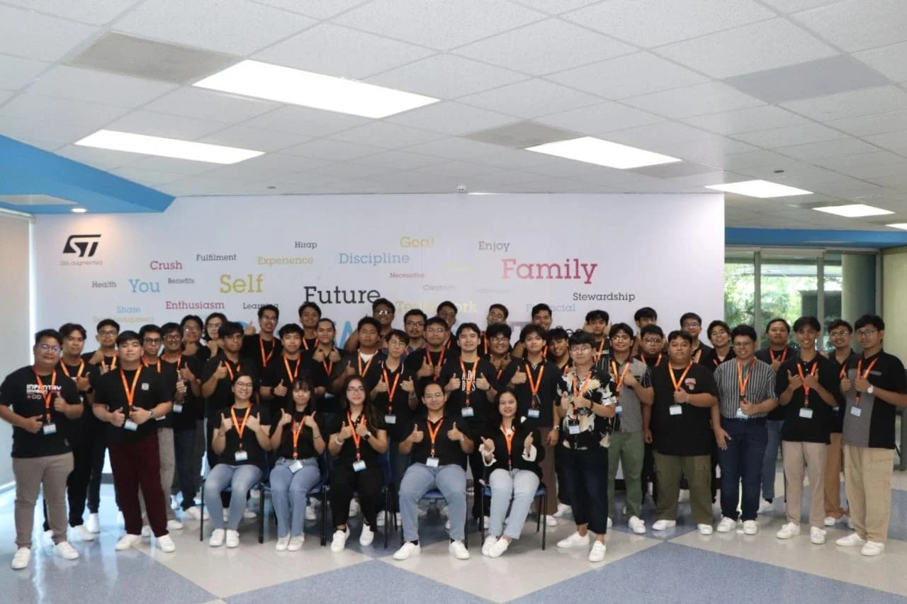 Group photograph inside STMicroelectronics, with the company logo on the wall.