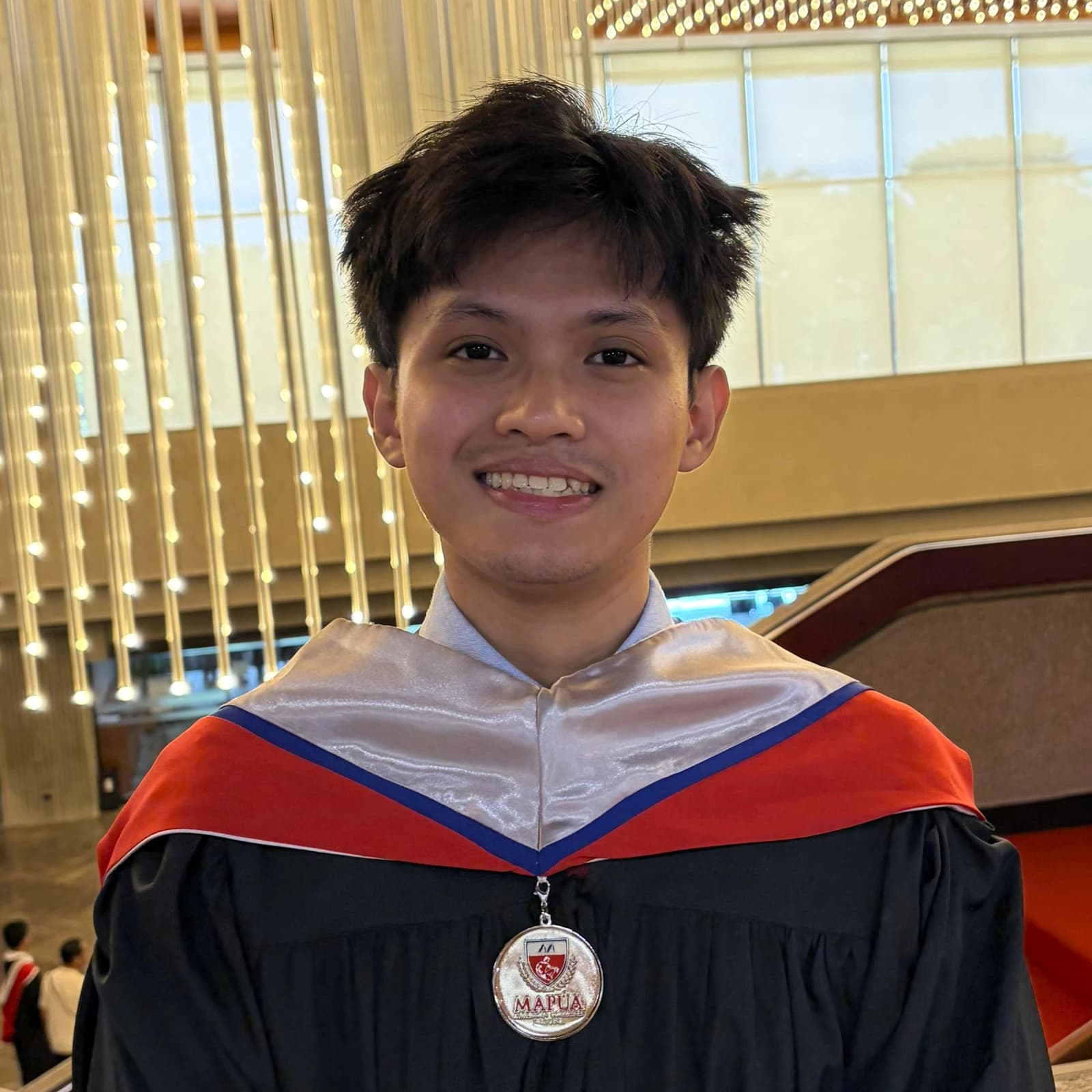 Rafael Doloso smiling in his graduation gown and Mapúa medallion.